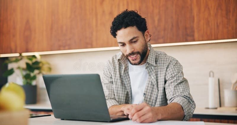 Man arbetar vid en laptop och antecknar vid ett köksbord